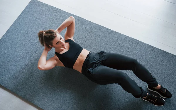 在垫子上在体育馆的地板上做腹肌 美丽的女健身者 — 图库照片
