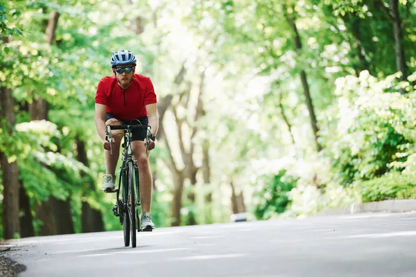 热的温度晴天 骑自行车的人在森林里的柏油路上 — 图库照片