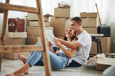 Belge okunuyor. Yeni dairelerinde neşeli genç bir çift. Taşınma kavramı.