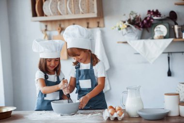 Beyaz şef üniformalı aile çocukları mutfakta yemek hazırlıyorlar..