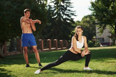 Erkeklerin güzel karın kasları var. Erkek ve kadının şehirde gündüz vakti parkta fitness günü var..