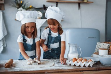 Beyaz şef üniformalı aile çocukları mutfakta yemek hazırlıyorlar..