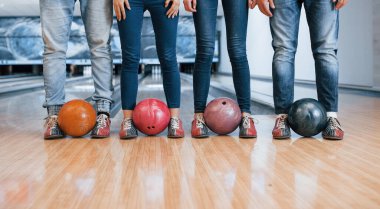 Topları bacaklarından tutarak. Bowling kulübündeki insanlar eğlenmeye hazır..