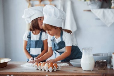 Beyaz şef üniformalı aile çocukları mutfakta yemek hazırlıyorlar..