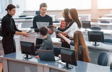 Gazetelerle çalışıyorum. Modern ofiste sıradan kıyafetler giyen bir grup genç..