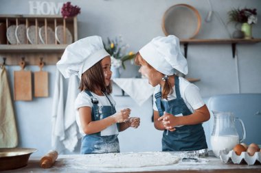 Süreç boyunca eğleniyorum. Beyaz şef üniformalı aile çocukları mutfakta yemek hazırlıyorlar..