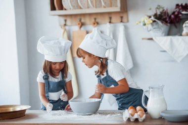 Beyaz şef üniformalı aile çocukları mutfakta yemek hazırlıyorlar..