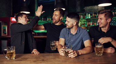 Barda elinde birayla dinlenen üç arkadaş. Sohbet ederken.