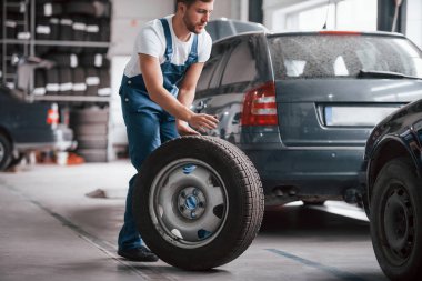 Az kaldı. Mavi üniformalı işçi otomobil salonunda çalışıyor..