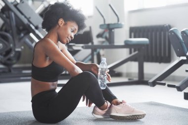 Düşünceli bir bakış. Kıvırcık saçlı ve spor elbiseli Afrikalı Amerikalı kadın spor salonunda spor yapıyor..