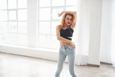 Dans hobisi kavramı. Çekici kızıl saçlı kadın pencerenin yanındaki uzay odasında poz veriyor..