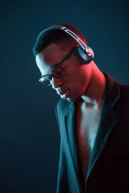 Kulaklıkla müzik dinlemeyi seviyorum. Gözlüklü. Fütürist neon ışıkları. Stüdyodaki Afrikalı Amerikalı genç adam..