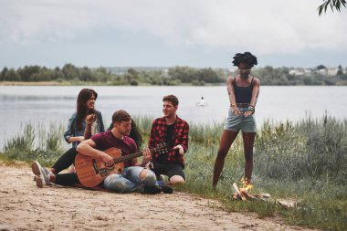 Hangi şarkıyı çalmamı istiyorsun? Bir grup insan sahilde piknik yapıyor. Arkadaşlar hafta sonu eğlenir..