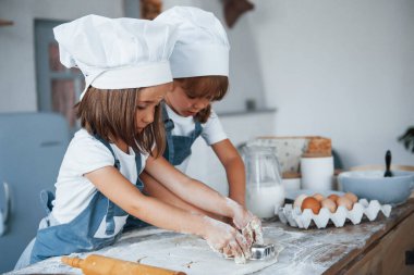 Yemek pişirmeye odaklan. Beyaz şef üniformalı aile çocukları mutfakta yemek hazırlıyorlar..