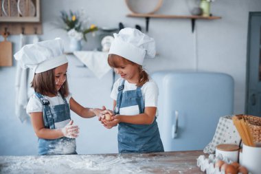 Yumurtalarla oynamak. Beyaz şef üniformalı aile çocukları mutfakta yemek hazırlıyorlar..