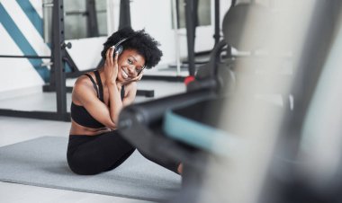 Ekipmanlar arasında. Kıvırcık saçlı ve spor elbiseli Afrikalı Amerikalı kadın spor salonunda spor yapıyor..
