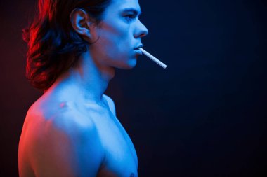 Yakışıklı adam. Stüdyo karanlık stüdyoda neon ışıkla çekiliyor. Ciddi bir adamın portresi..