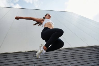 Alt manzara. Genç sporcu kadın güneşli bir günde şehirde parkçılık yapıyor..