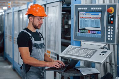 Fabrikada sanayi işçisi. Turuncu şapkalı genç teknisyen..