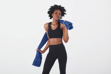 Elinde mavi renkli havluyla. Stüdyoda beyaz arka planda güzel bir Afro-Amerikan kadın var..