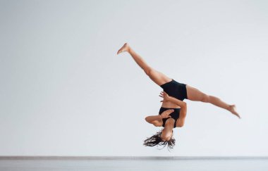 Çılgınca numaralar yapıyor. Siyah elbiseli, zayıf vücutlu genç, sportif bir kadın. Sağlık merkezinde egzersiz yapıyor..