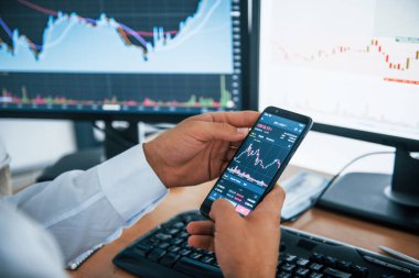 Erkeklerin elinde tuttuğu telefonların yakın görüntüsü. İşadamı birden fazla ekranla ofiste. Değişim ve para kavramı.