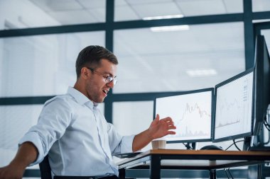 Kızgın çalışan kâğıt fırlatıyor. Başarısızlık kavramı. Resmi giyinmiş genç işadamı birden fazla ekranla ofiste..