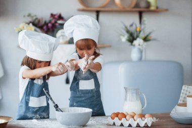 Beyaz şef üniformalı aile çocukları mutfakta yemek hazırlıyorlar..
