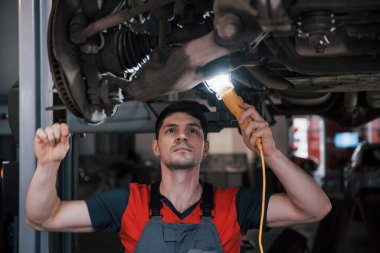 Sorun çok yakında çözülecek. Atölyedeki üniformalı adam modern arabanın kırık parçalarını tamir ediyor..