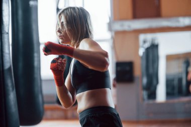 Agresif tekme. Dişi boksör torbayı yumrukluyor. Sarışın spor salonunda egzersiz yapıyor..
