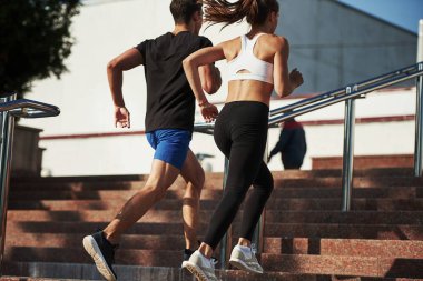 Merdivenlerde. Erkek ve kadının spor günleri var ve şehirde gündüz koşuyorlar..