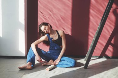 Güzel gün ışığı. Genç ev hanımı, odadaki yeni evine duvar kağıdı yapıştırmaya karar verdi..