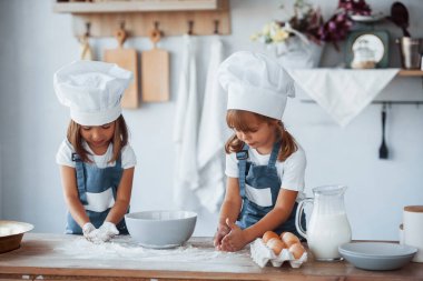 Beyaz şef üniformalı aile çocukları mutfakta yemek hazırlıyorlar..