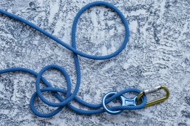 İlginç bir geçmiş. Tırmanma ekipmanlarının izole edilmiş fotoğrafı. Karabinanın bir kısmı beyaz ve gri renkli yüzeyde yatıyor..