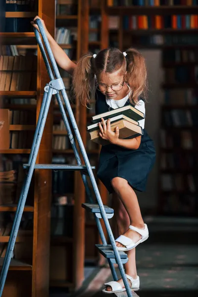 Schulmädchen Auf Der Leiter Der Bibliothek Voller Bücher Bildungskonzept — Stockfoto