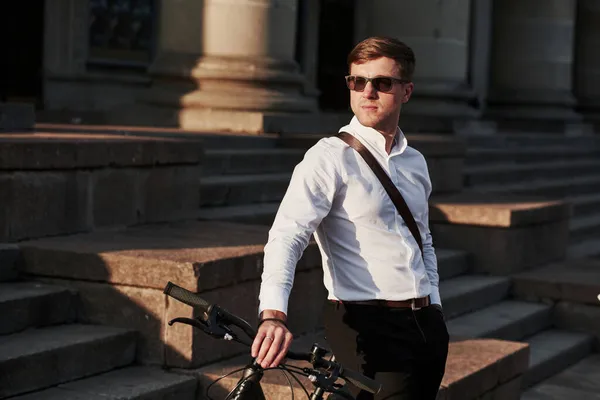 日の出を見て 黒い自転車の正式な服を着たビジネスマンが街にいます — ストック写真
