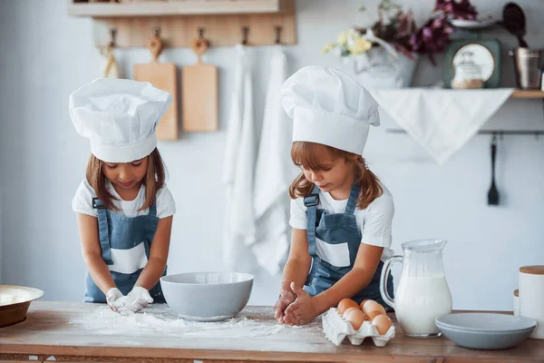 Beyaz şef üniformalı aile çocukları mutfakta yemek hazırlıyorlar..