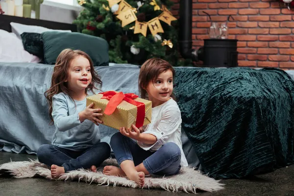 送给这两个坐在床上漂亮房间里的孩子们的圣诞节礼物 — 图库照片