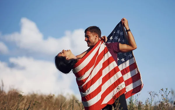 感觉自由 有美国国旗的年轻夫妇在田野里玩得很开心 — 图库照片