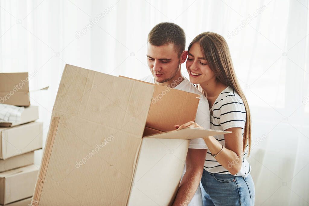 Carrying the box. Cheerful young couple in their new apartment. Conception of moving.