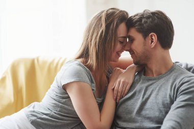 İyi hissediyorum. Mutlu çift yeni evlerinin oturma odasındaki sarı kanepede dinleniyor..