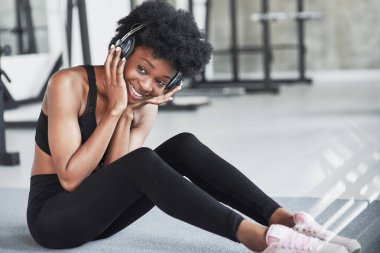 Komik ve mutlu bir kız. Kıvırcık saçlı ve spor elbiseli Afrikalı Amerikalı kadın spor salonunda spor yapıyor..
