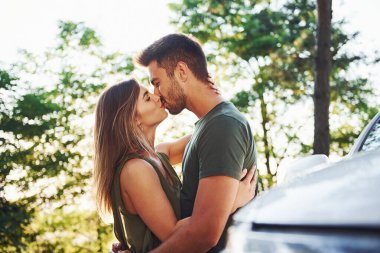 Beyaz arabanın ön tarafında. Genç ve güzel bir çift gündüz vakti ormanda iyi vakit geçirir..