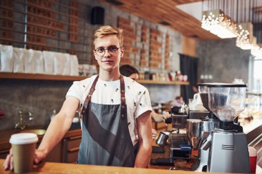 İçkini al lütfen. Genç erkek kafe çalışanı içeride. İş ve hizmet kavramı.