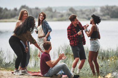 Birbirleriyle sohbet ediyorlar. Bir grup insan sahilde piknik yapıyor. Arkadaşlar hafta sonu eğlenir..