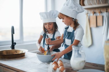 Beyaz şef üniformalı aile çocukları mutfakta yemek hazırlıyorlar..