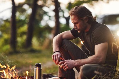 Taze ve sıcak içecek. Hafta sonu kamp ateşinin yanında siyah gömlekli bir adam vardı..
