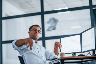 Kızgın çalışan kâğıt fırlatıyor. Başarısızlık kavramı. Resmi giyinmiş genç işadamı birden fazla ekranla ofiste..