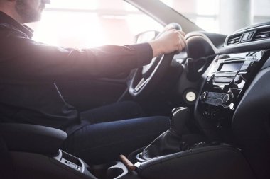 Muhteşem güneş ışığı. Modern bir arabada siyah iç mekanı olan bir adamın yan görüntüsü..