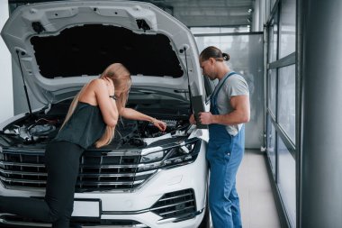 Yardım etmeme izin ver. Onarım sonuçları. Arabasının ne kadar hasar gördüğünü gösteren kendine güvenen bir adam..